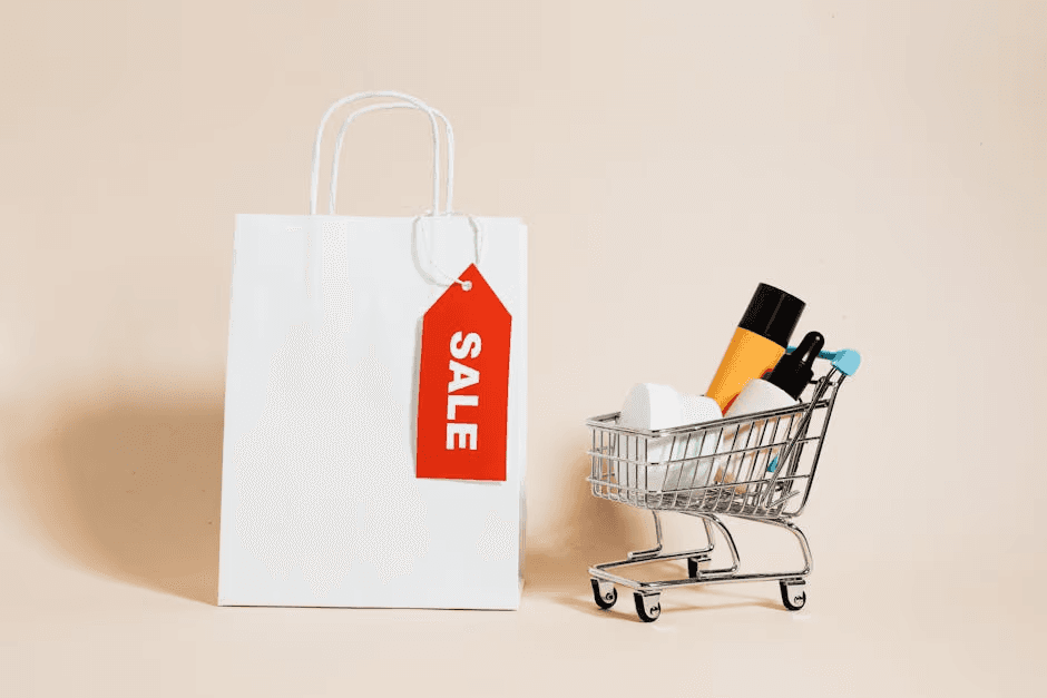White shopping bag with red sale tag and mini shopping cart on beige background